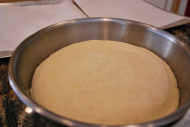 An in process image showing the dough after it has risen, puffed up, and doubled in size in the metal bowl.