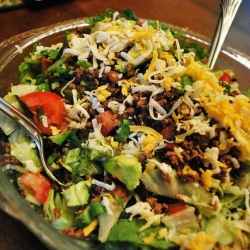 A close up image of Taco Salad in a glass serving bowl.