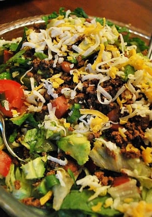 A close up image of Taco Salad in a glass serving bowl.