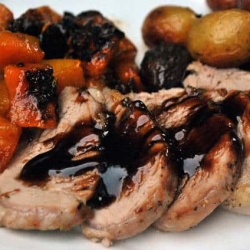 A serving of pork tenderloin with carrots and potatoes.