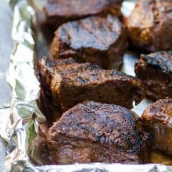 Grilled steaks on a foil lined baking sheet.