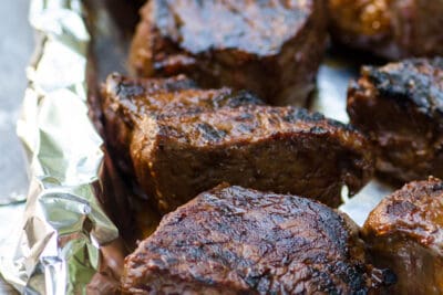 Grilled steaks on a foil lined baking sheet.