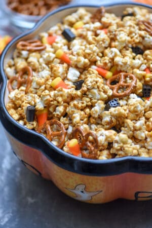 A side view of a Halloween themed bowl filled with caramel popcorn.