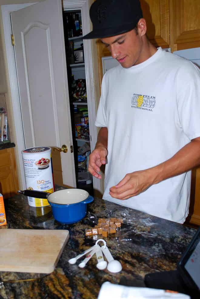 Valerie's son, Connor, unwrapping caramels at the kitchen counter. Connor is wearing a white tshirt and black baseball cap.Caramel Oat Bars