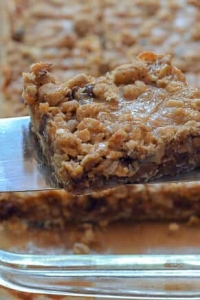 A caramel oat bar being lifted by a spatula.