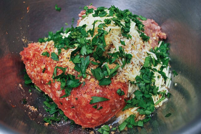 Lean ground beef, hot Italian sausage, a couple of eggs, some Italian style panko bread crumbs, Parmesan, fresh parsley, salt and pepper are combined in a metal mixing bowl.