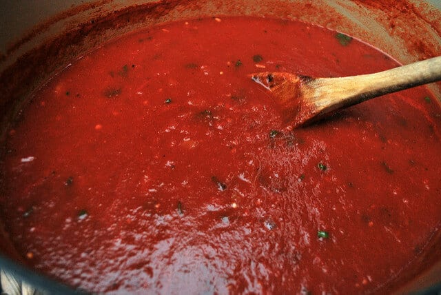 An in process image showing the basic red sauce simmering in a Dutch oven.