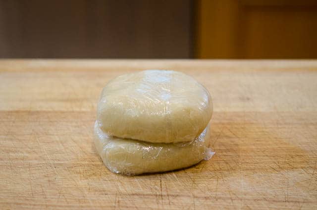 The balls of pastry dough are flattened into discs and wrapped in plastic wrap.