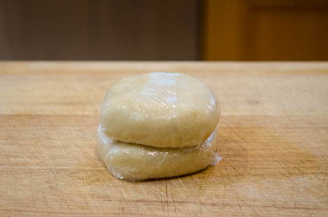 The balls of pastry dough are flattened into discs and wrapped in plastic wrap.