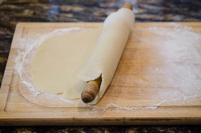 The dough is wrapped around the rolling pin so it can be transferred to the pie dish.