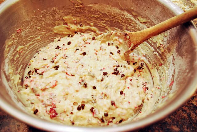 Cranberries and chocolate chips are added to the muffin batter in the mixing bowl.