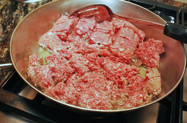 The meat is cooked in a large skillet.