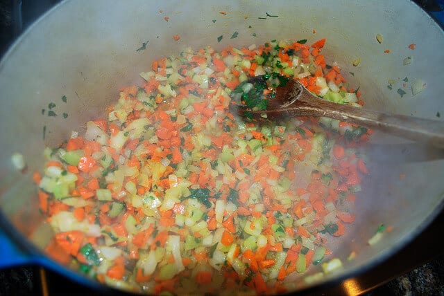 Carrots, onions, celery and parsley are sauteed in a large Dutch oven.