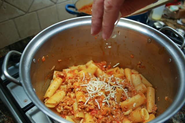 Parmesan cheese is sprinkled into the pot to top the Pasta Bolognese