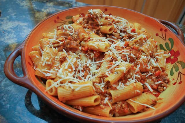 Pasta Bolognese in a patterned serving bowl topped with Parmesan cheese.