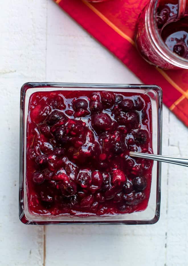 A over the top image of Very Berry Cranberry Sauce in a square glass serving dish with a spoon.