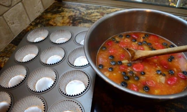 A metal bowl full of the Frozen Fruit Salad next to a muffin pan filled with foil cupcake liner.