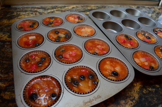 The Frozen Fruit Salad is divided between the foil cupcake liners in the muffin pans.