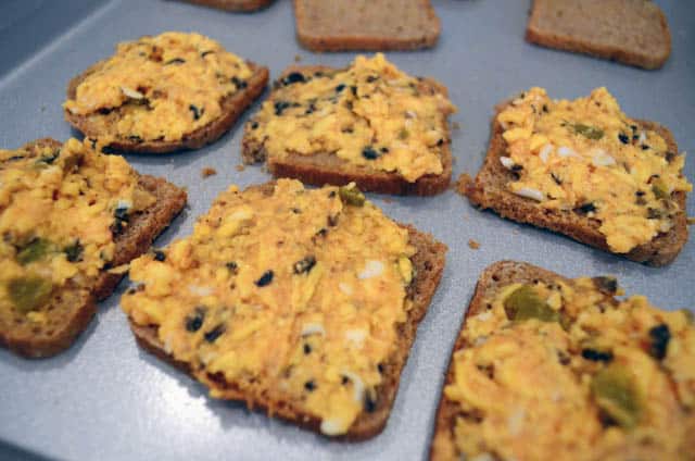 The cheese mixture is spread on to pieces of cocktail rye bread and placed on a baking sheet.