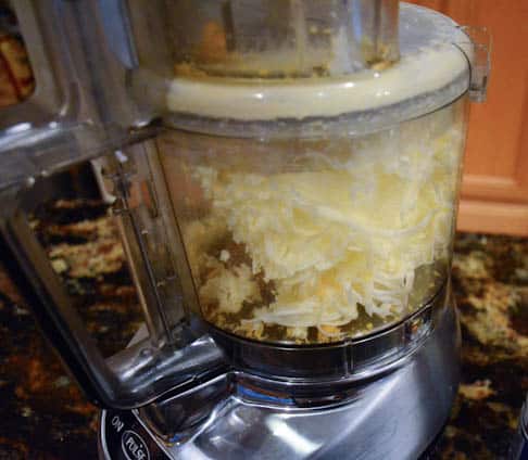 A stick of butter is grated in a food processor.