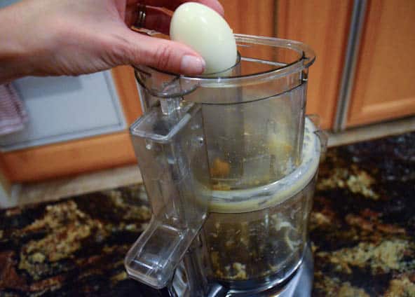 A hard boiled egg is grated in a food processor.