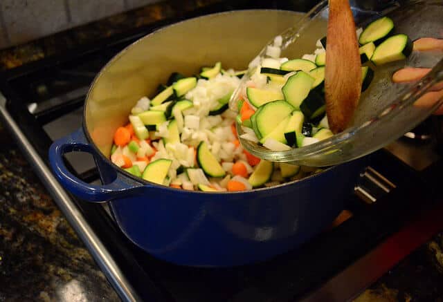 Chopped vegetables in a dutch oven on a stove top.