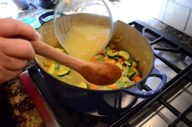 Chicken broth being added into the dutch oven.