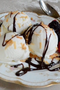 A serving of ice cream with berries and chocolate syrup.
