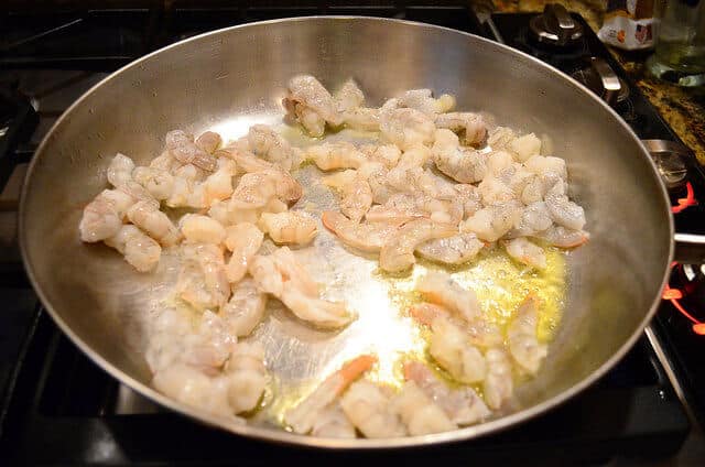 Shrimp cooking in a pan with olive oil.