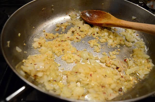 A pan with olive oil and diced onion, crushed red pepper and garlic.