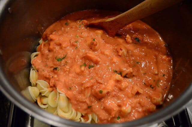 The sauce is added to the pot of cooked pasta.