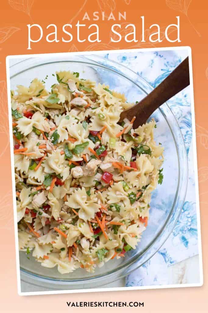 A spoon resting in a bowl of Asian pasta salad with text overlay.