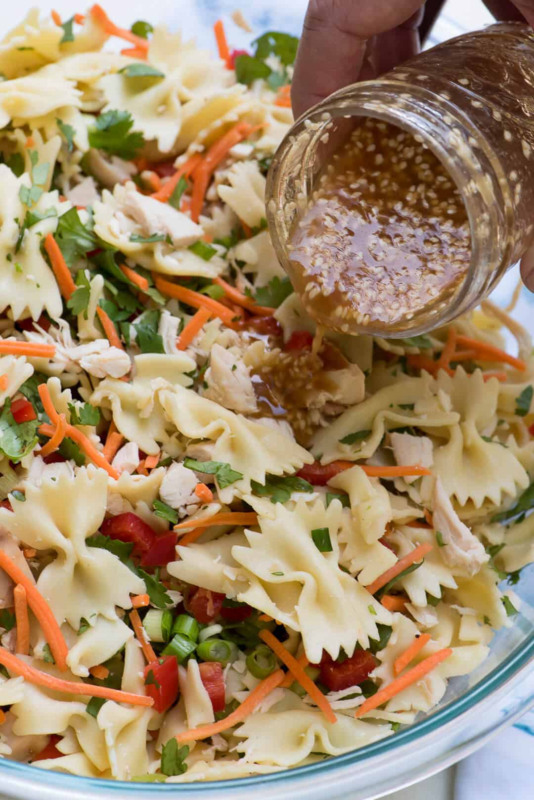 Dressing being poured from a small mason jar on top of the salad.