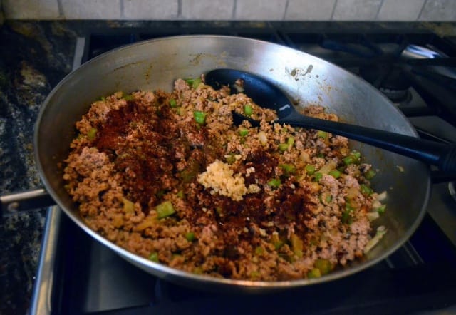 Garlic and spices are added to the meat mixture in the skillet.