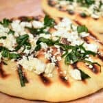 A close up of flatbread with feta and basil on top.