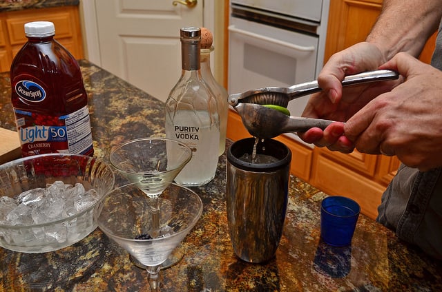 Half a lime is squeezed into the shaker using a citrus juicer.