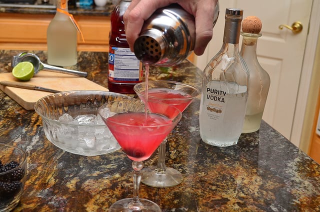 The cosmopolitan being poured from the shaker into a martini glass.