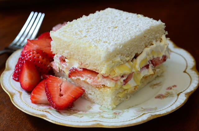 A slice of cake with a side of strawberries.
