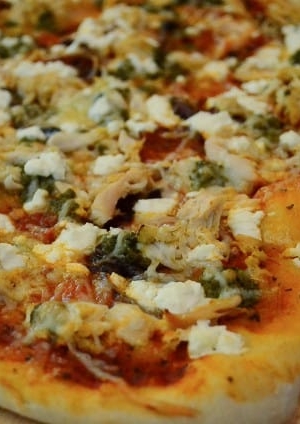 A close up of chicken pesto pizza.