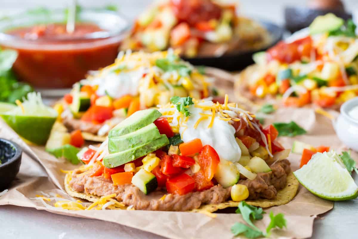 A close up side view of a tostada with beans and vegetables.