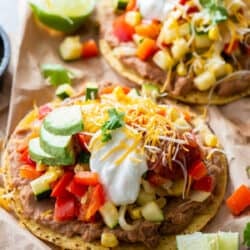 Two vegetarian tostadas topped with cheese and sour cream.