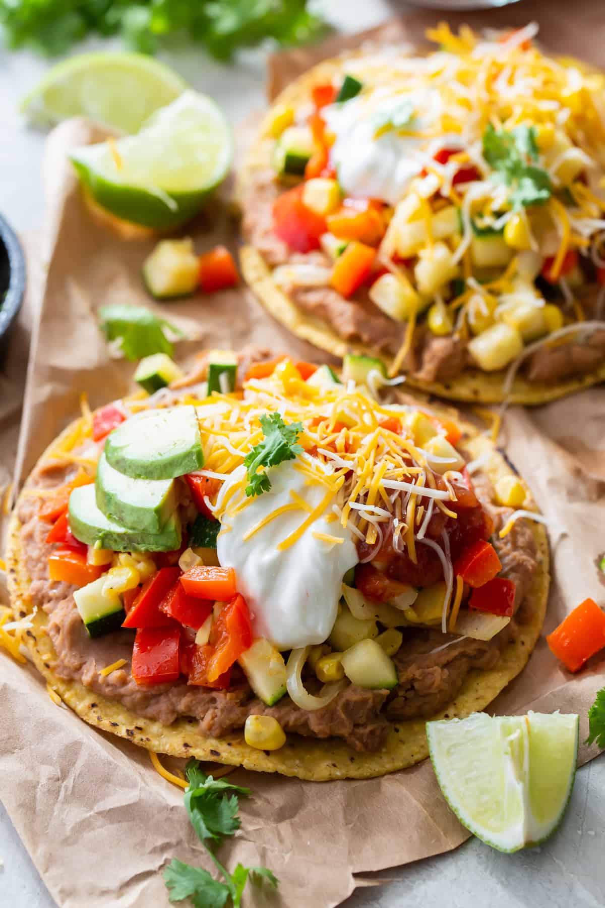 Two vegetarian tostadas topped with cheese and sour cream.