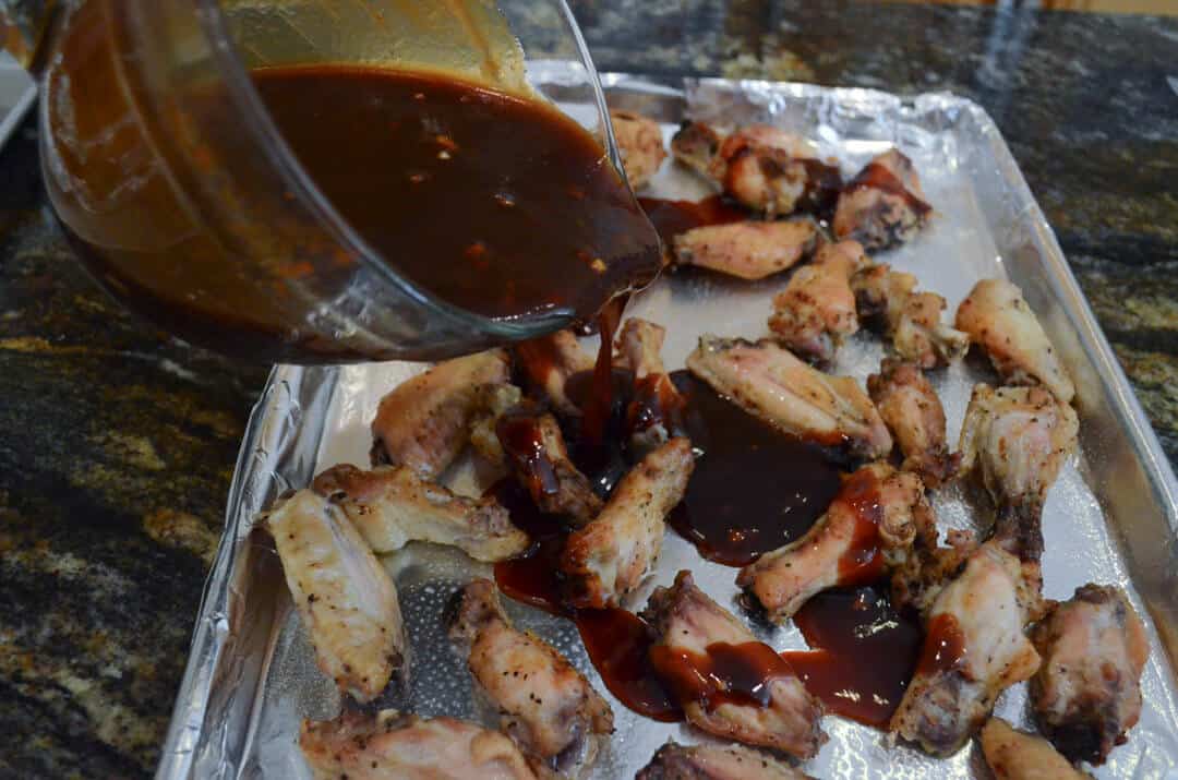 The chicken wing sauce being poured over the chicken wings.