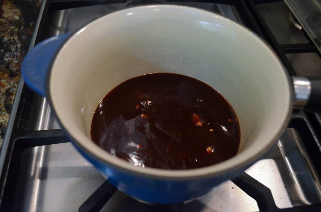 The remaining chicken wing sauce simmering on a stove.