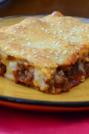 A sloppy joe square on a yellow plate.