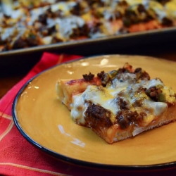 A slice of cheeseburger pan pizza on a yellow plate.