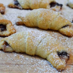 A close up of crescent rolls stuffed with chocolate a dusted with powdered sugar.