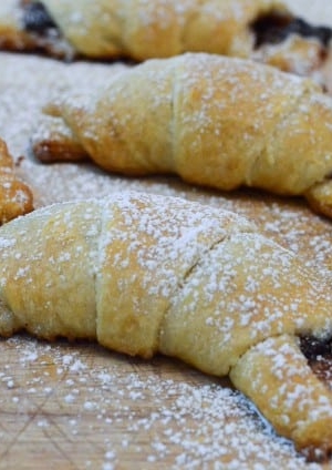 A close up of crescent rolls stuffed with chocolate a dusted with powdered sugar.