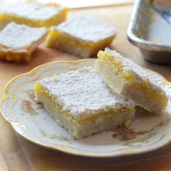 Two lemon bars stacked on a china plate.