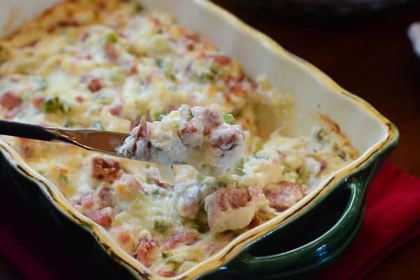 A knife lifts some kielbasa dip from a serving dish.